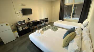 Habitación de hotel con dos camas, un escritorio, un televisor de pantalla plana, un microondas y un refrigerador.