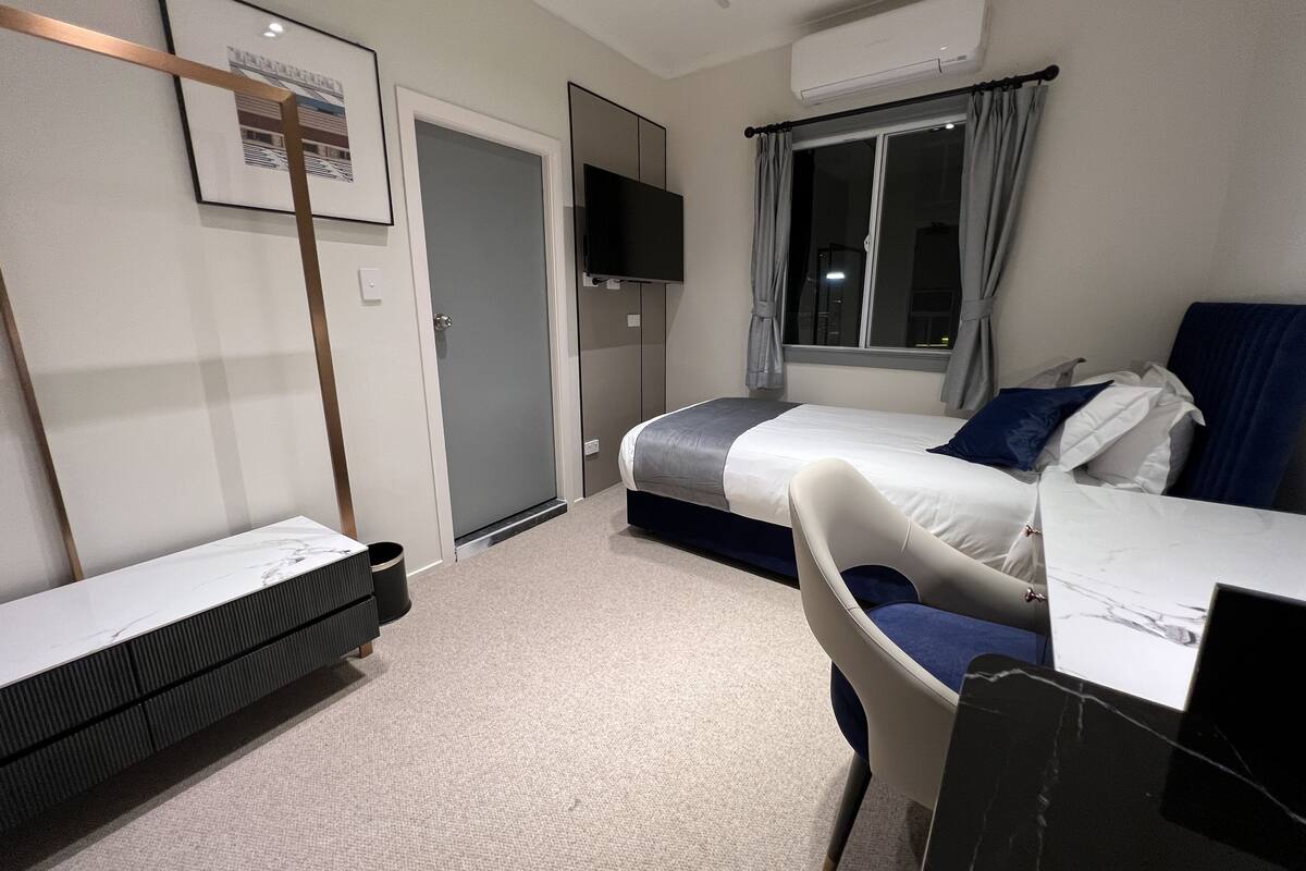Une chambre d’hôtel équipée d’un lit, d’un bureau, d’une chaise, d’une télévision et d’un appareil de climatisation.