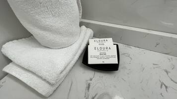 Un baño con una toalla blanca y una barra de jabón ELOURA Australia sobre una encimera de mármol.