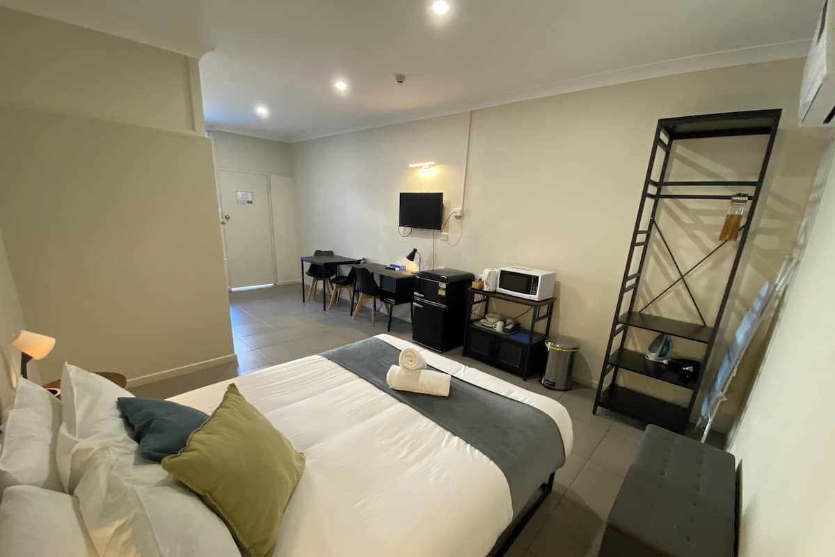 Une chambre d’hôtel équipée d’un lit, d’un bureau, d’une chaise et d’un téléviseur fixé au mur.