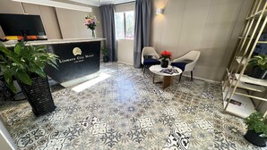 A reception area with a reception desk, a television, a potted plant, and a seating area with two chairs and a table. - Lismore City Motor Inn (Lismore)