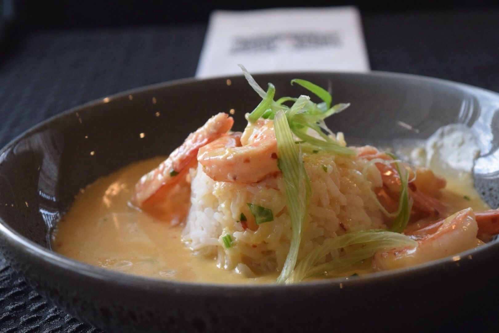A bowl of rice with shrimp and vegetables in a creamy sauce.