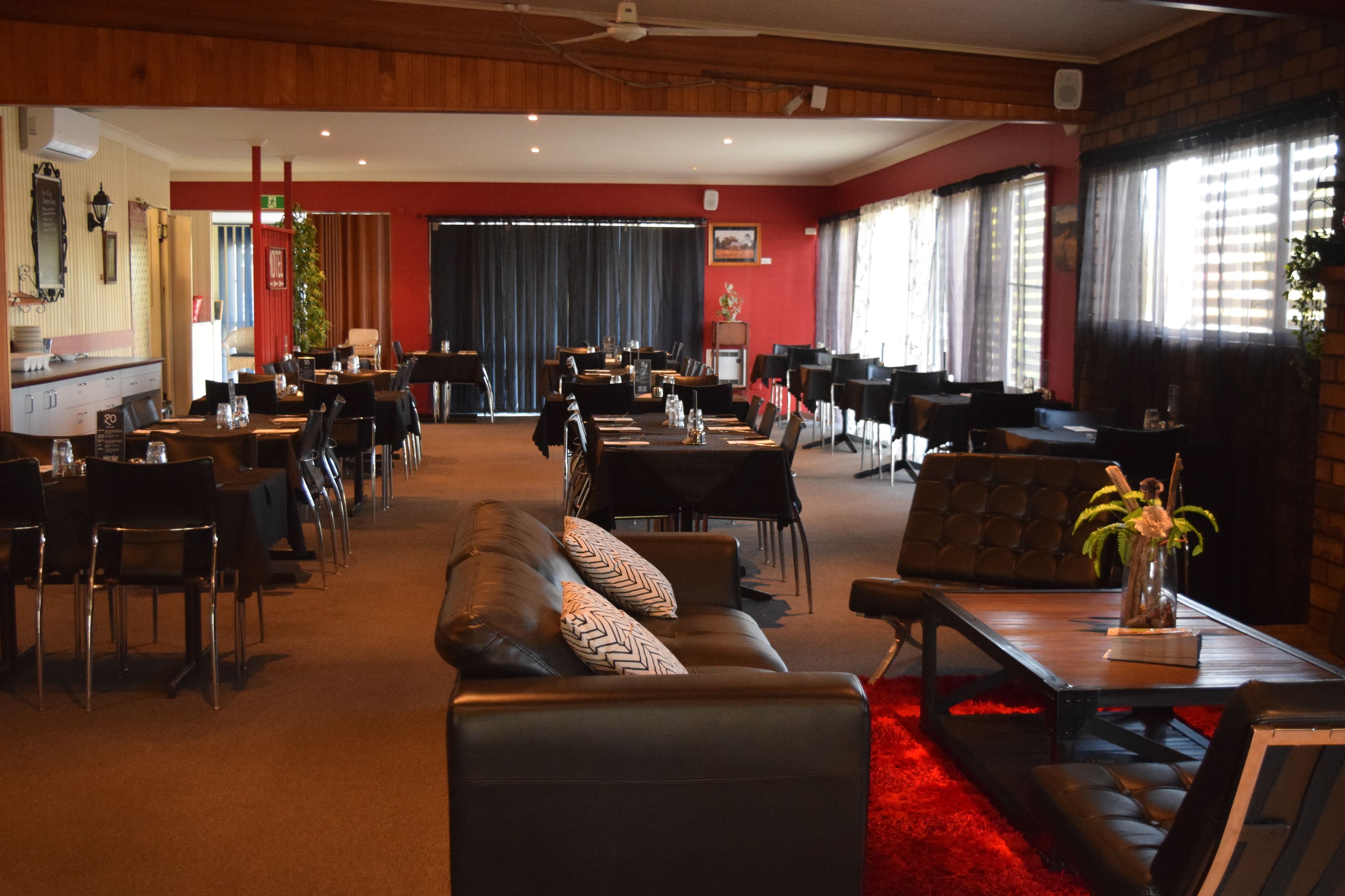 Eine großzügige Hotelhalle mit mehreren Essbereichen, Ledersitzgelegenheiten und großen Fenstern.