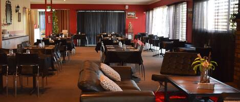 Un'ampia hall dell'hotel con diverse aree ristorazione, sedute in pelle e ampie finestre.