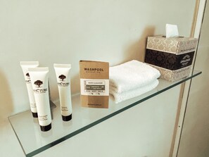 A bathroom shelf with a body cleanser, two tubes of conditioner, a box of shampoo, and a box of toilet paper.