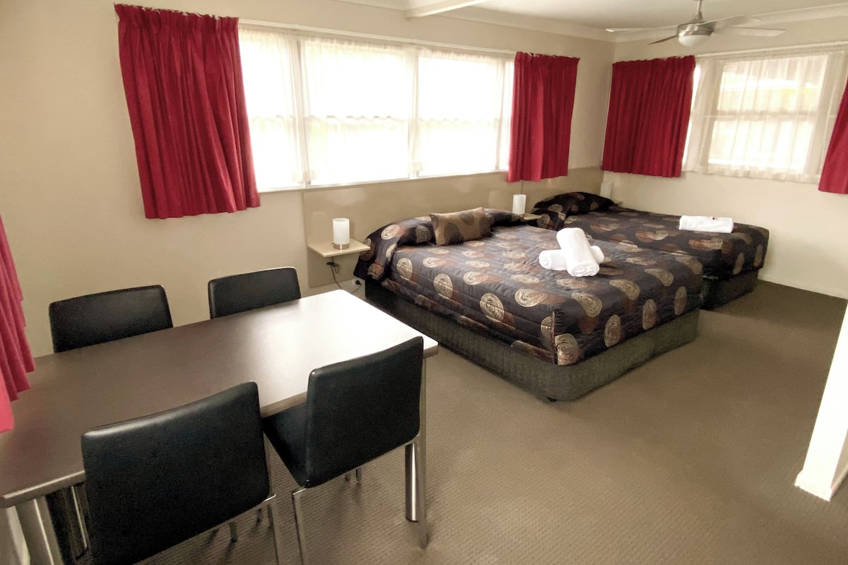 A hotel room with a bed, a desk, and chairs.