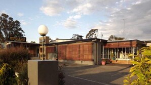 A motel with a modern design, featuring a large spherical light fixture and a covered outdoor seating area.