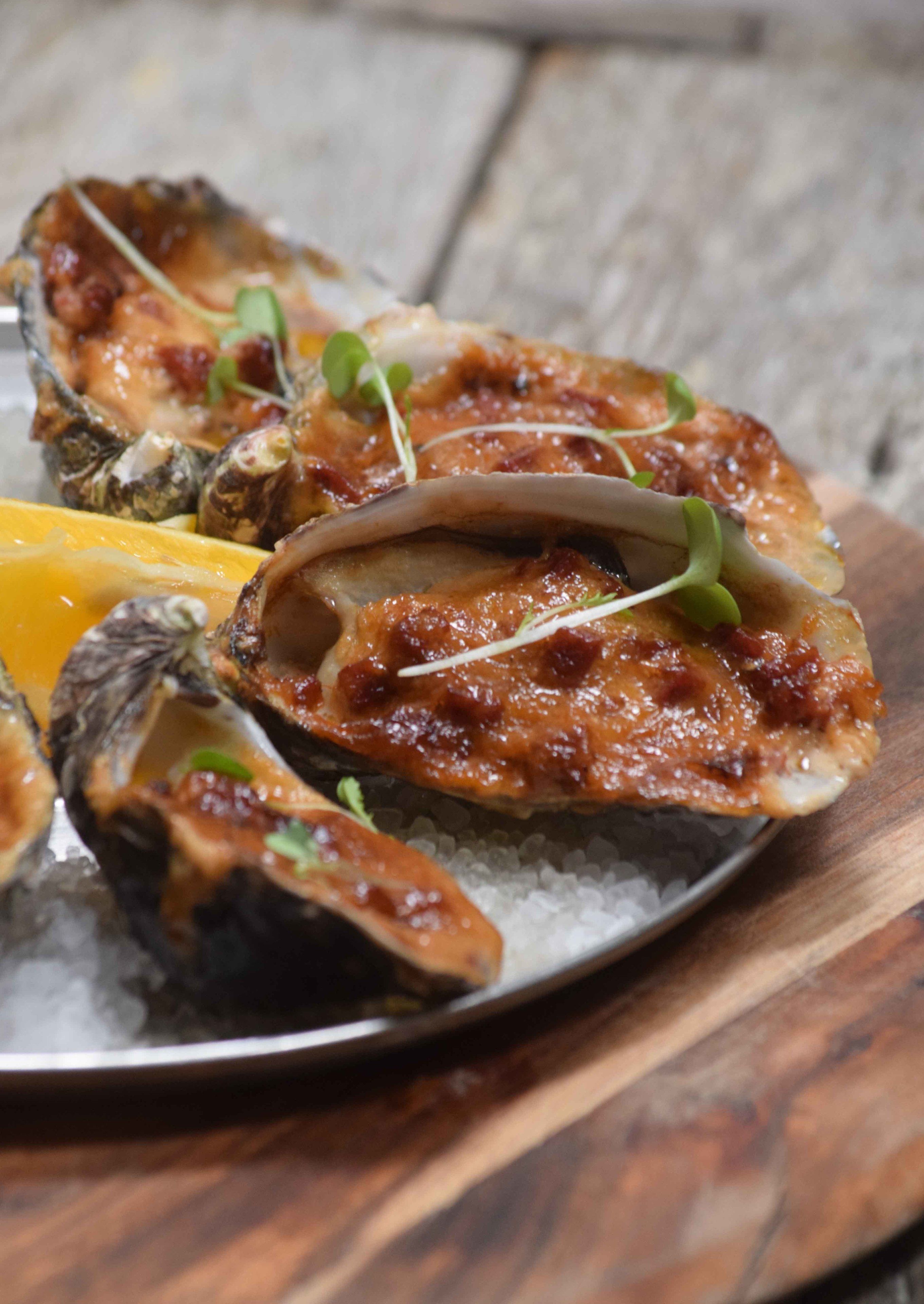A plate of oysters on the half shell with a garnish of microgreens, served on a bed of coarse salt.