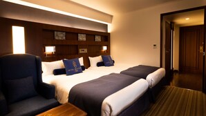 A hotel room with two beds, a chair, and a wooden side table. - Hotel Bellclassic Tokyo (Tokyo)