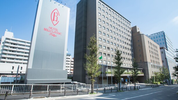 A modern hotel building with a prominent vertical sign featuring a logo and the name "Hotel Bellglas." - Hotel Bellclassic Tokyo (Tokyo)