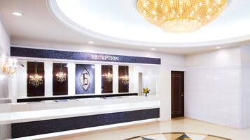Ett entréområde med en receptionsdisk, en kristallkrona och ett klinkergolv.