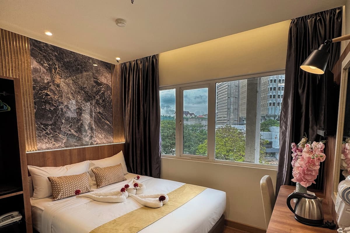 Een moderne hotelkamer met een groot bed, een houten bureau, uitzicht op de stad en een marmeren wand.
