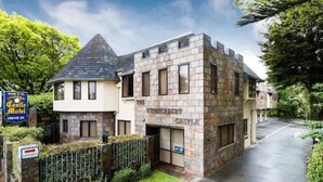 A castle-themed hotel with a stone facade, a drive-in entrance, and a well-maintained lawn. - Fitzherbert Castle Motel (Palmerston North)