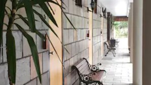 A covered walkway with stone flooring, a potted plant, and a bench. - Fitzherbert Castle Motel (Palmerston North)