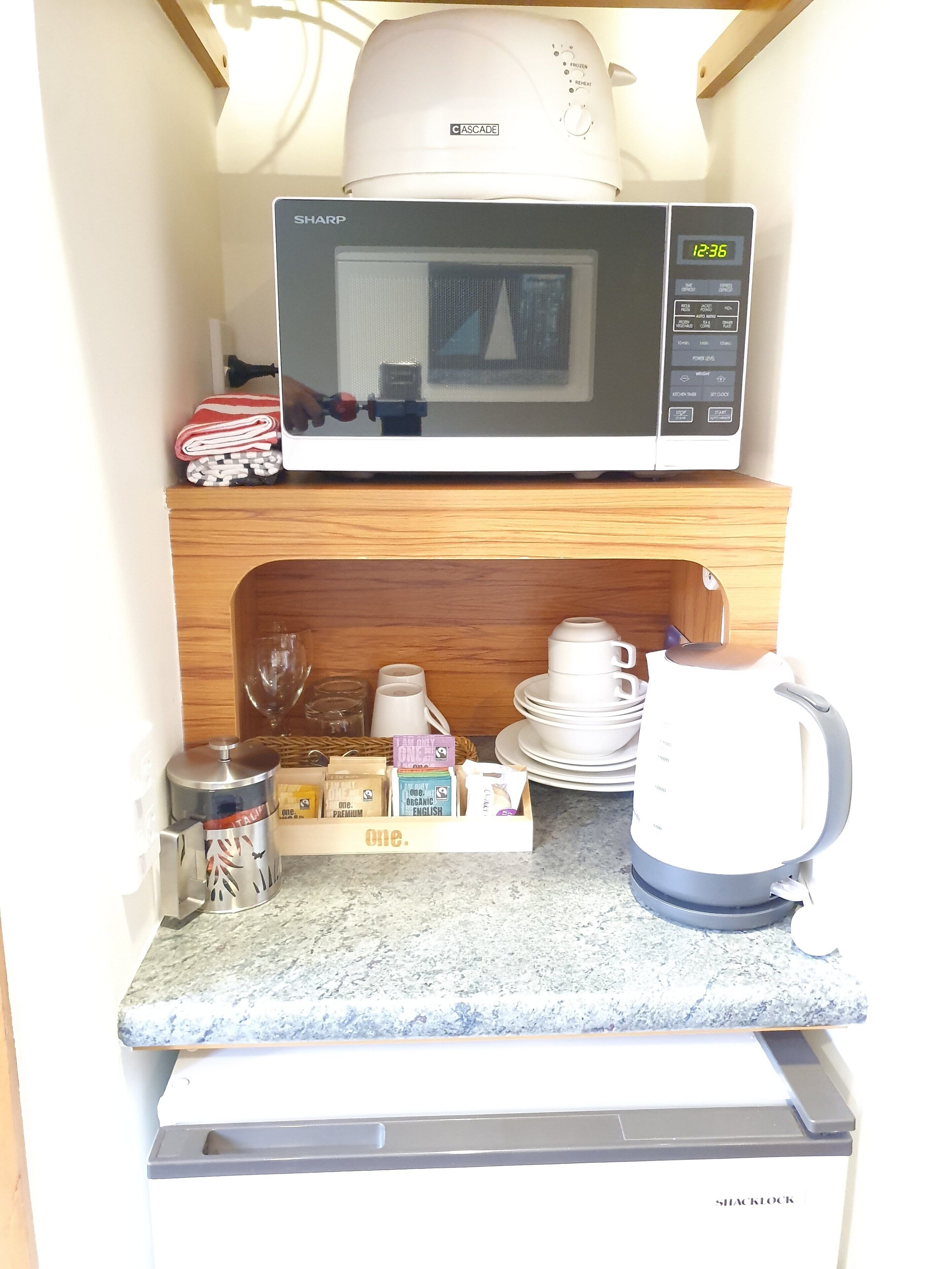 Una cocina compacta equipada con microondas, cafetera y refrigerador pequeño.