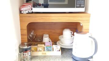 A compact kitchen with a microwave, coffee maker, and a small refrigerator.