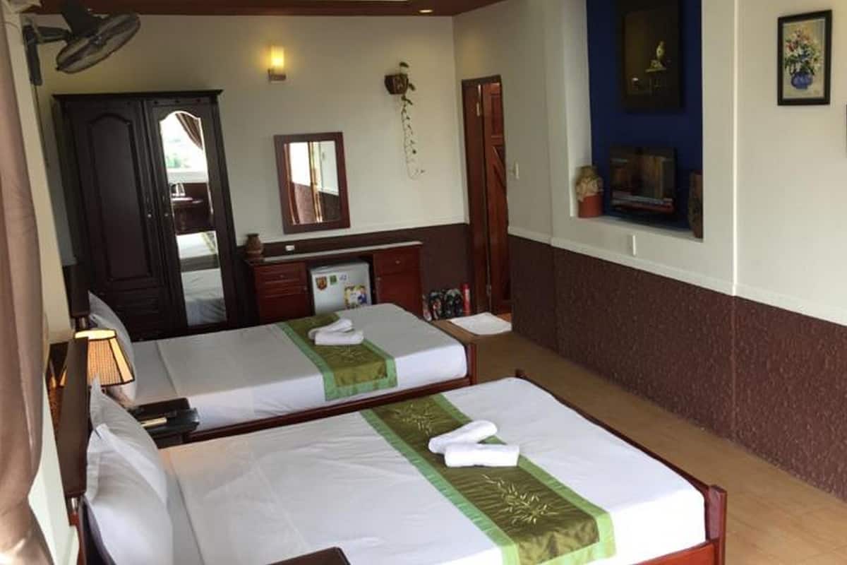 Habitación de hotel con dos camas, un escritorio, un espejo y un ventanal pequeño.