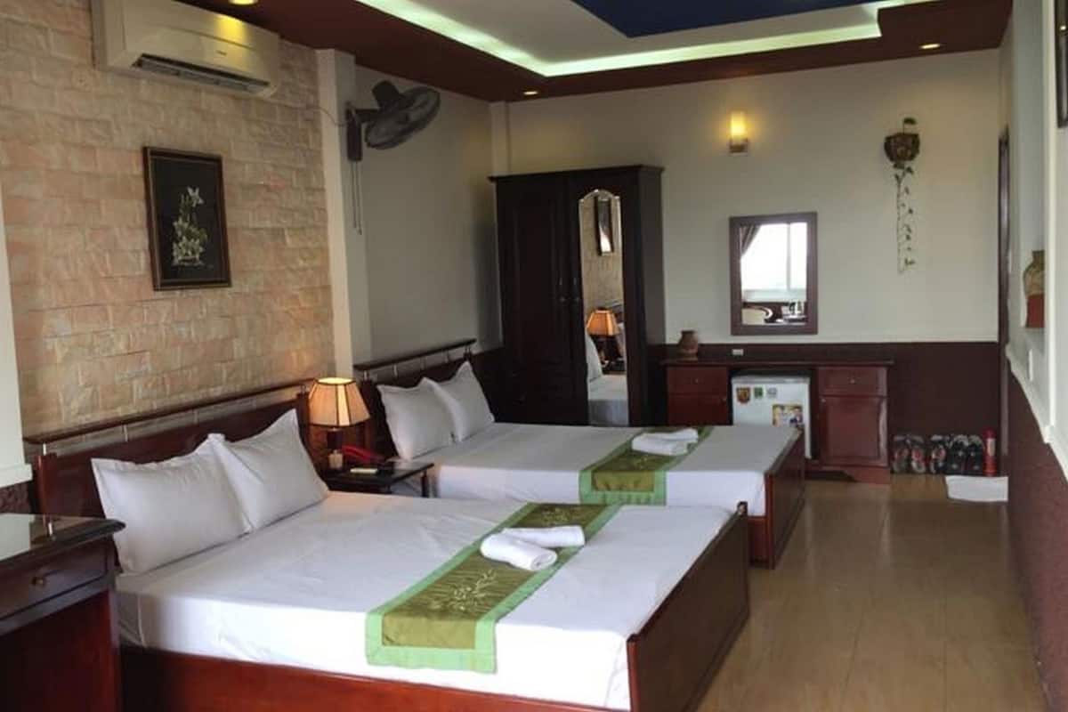 Una habitación de hotel con dos camas, un escritorio, un espejo y una pared de piedra.