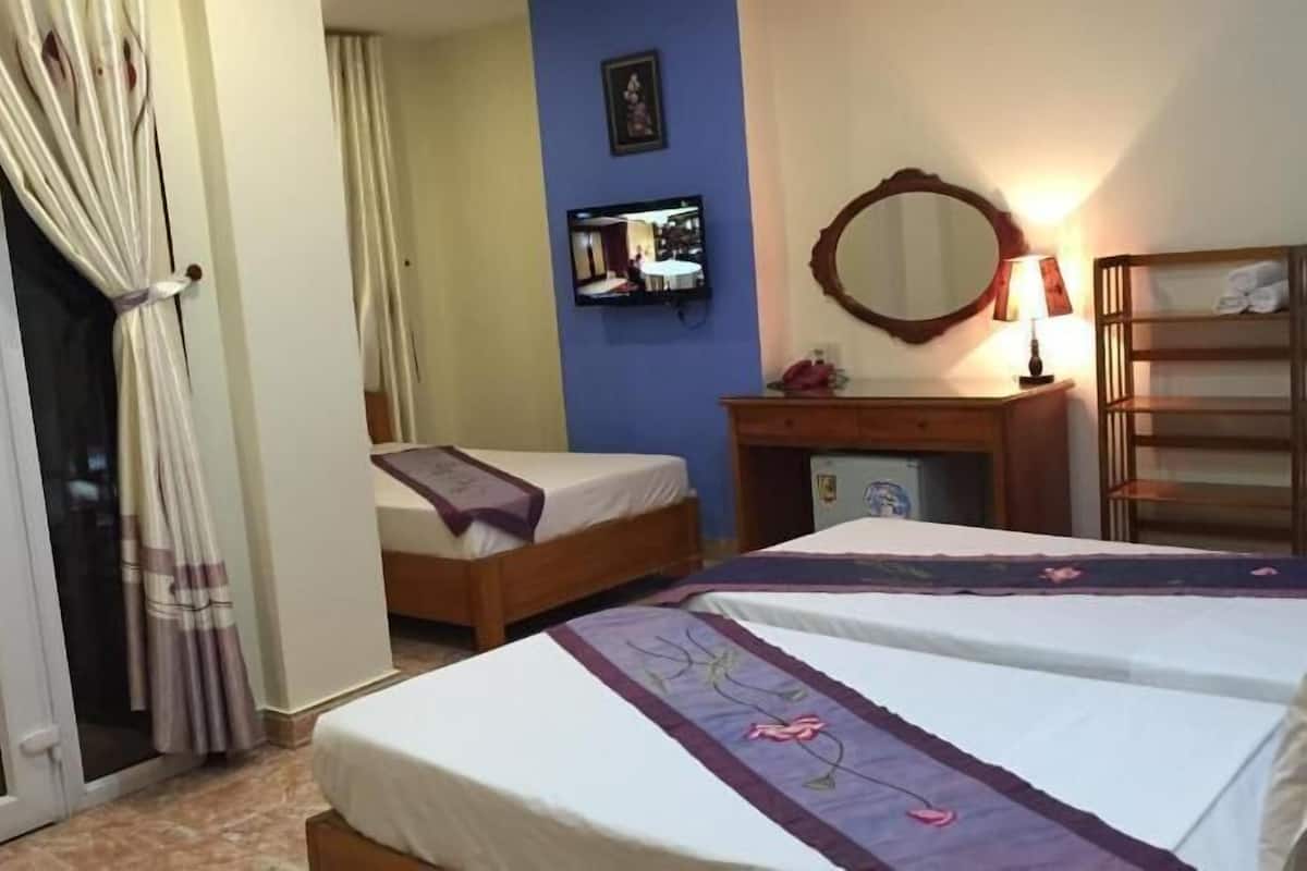 Habitación de hotel con dos camas, televisor, espejo, escritorio y armario.