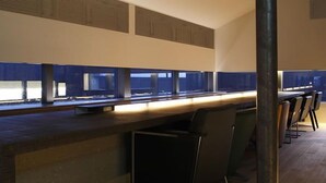 Uma área de bar moderna com um balcão comprido e vários banquinhos.