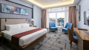 A hotel room with a large bed, a desk with a chair, a small table, and a TV. - Sunlight Guest Hotel (Puerto Princesa)