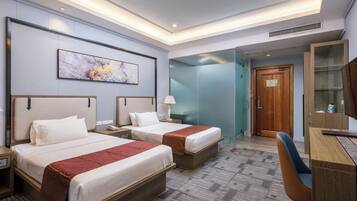 A hotel room with two beds, a desk, a chair, a large painting on the wall, and a glass partition.