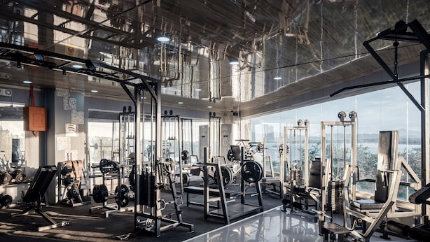 A modern gym with various exercise equipment, large windows, and a high ceiling. - Sunlight Guest Hotel (Puerto Princesa)