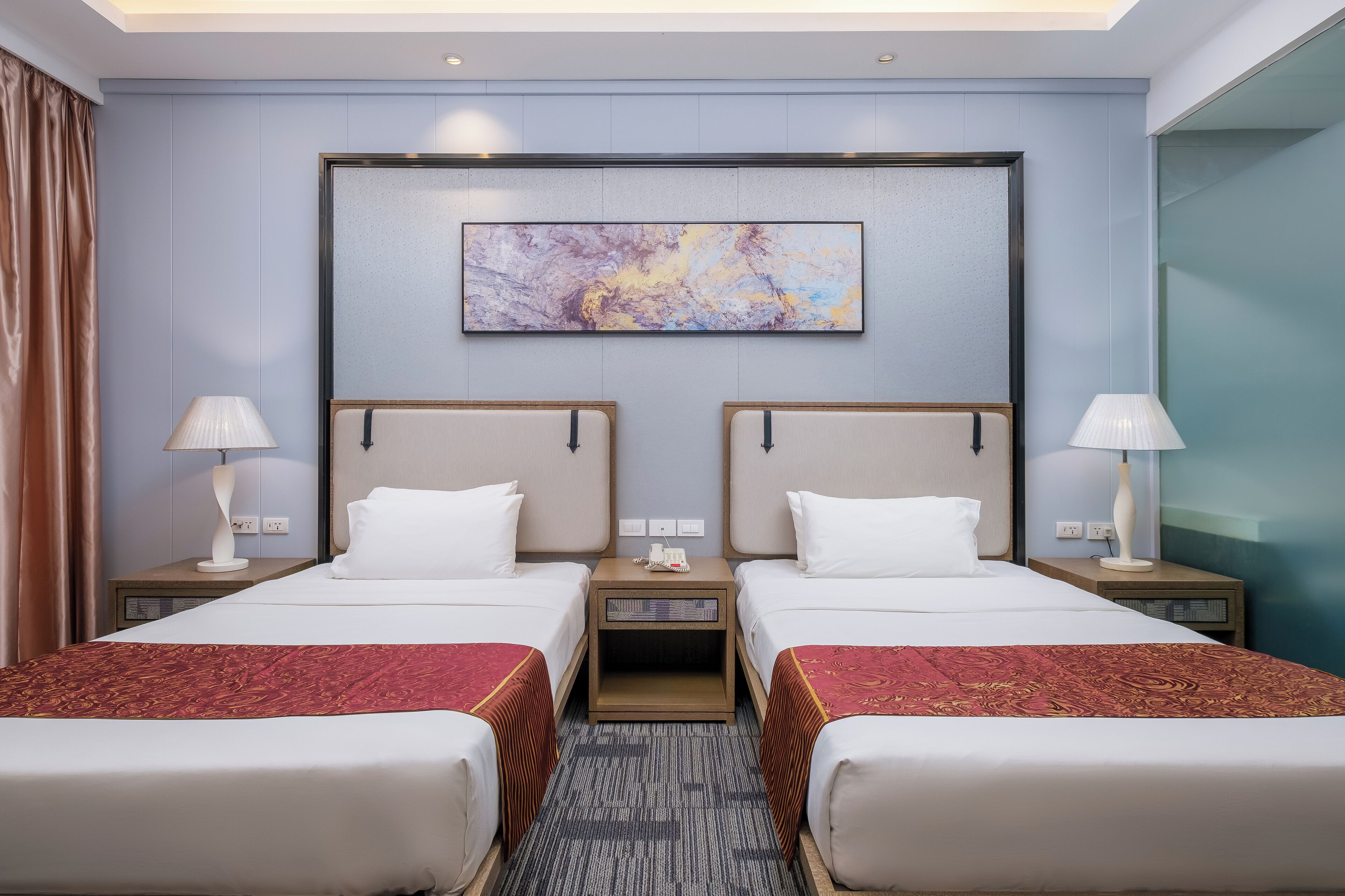 Una habitación de hotel con dos camas, un cuadro abstracto grande en la pared y piso alfombrado.