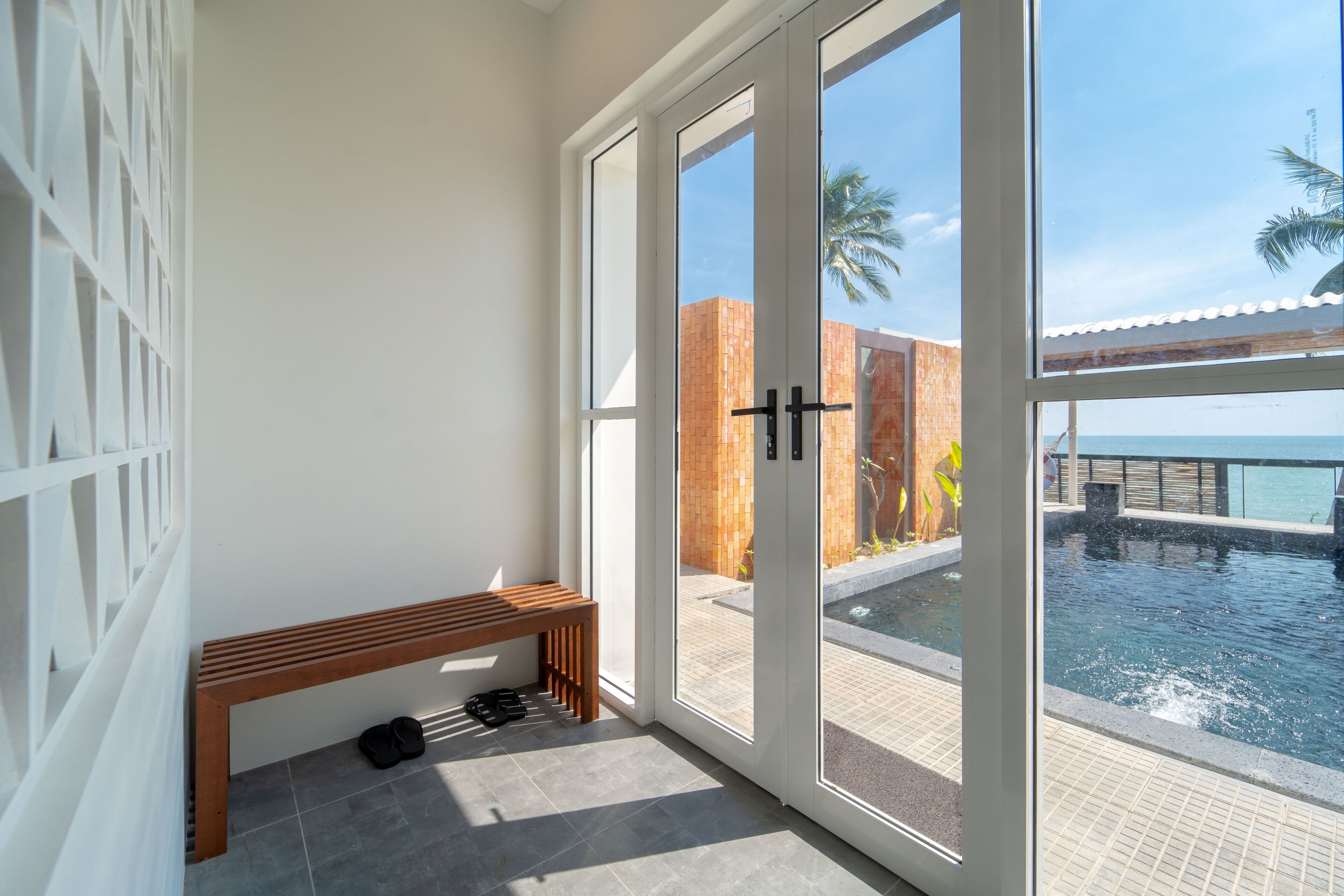A balcony with a bench, a pool, and a view of the ocean.