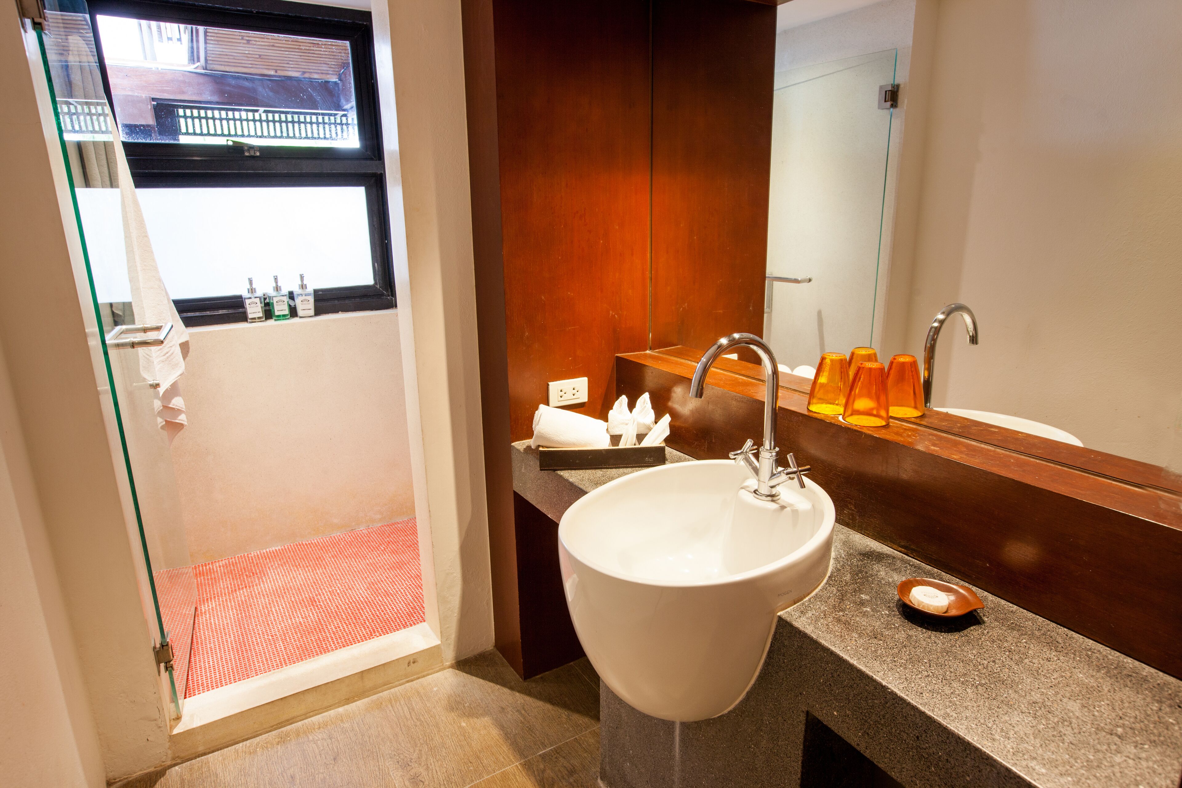 Un baño con un lavamanos grande, un espejo y una cabina de ducha de vidrio.