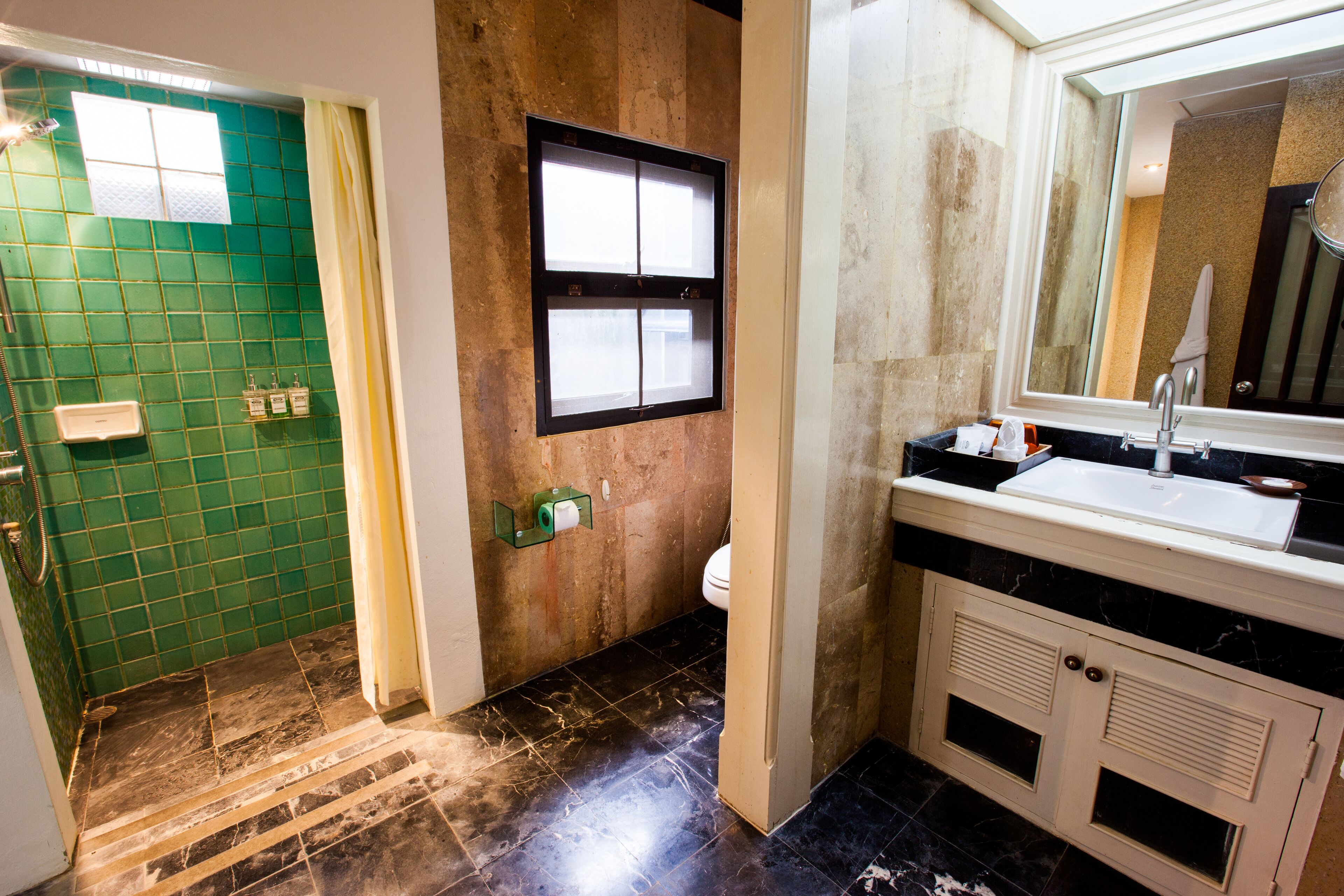 A bathroom with a green tiled wall, a white sink, and a mirror above it.