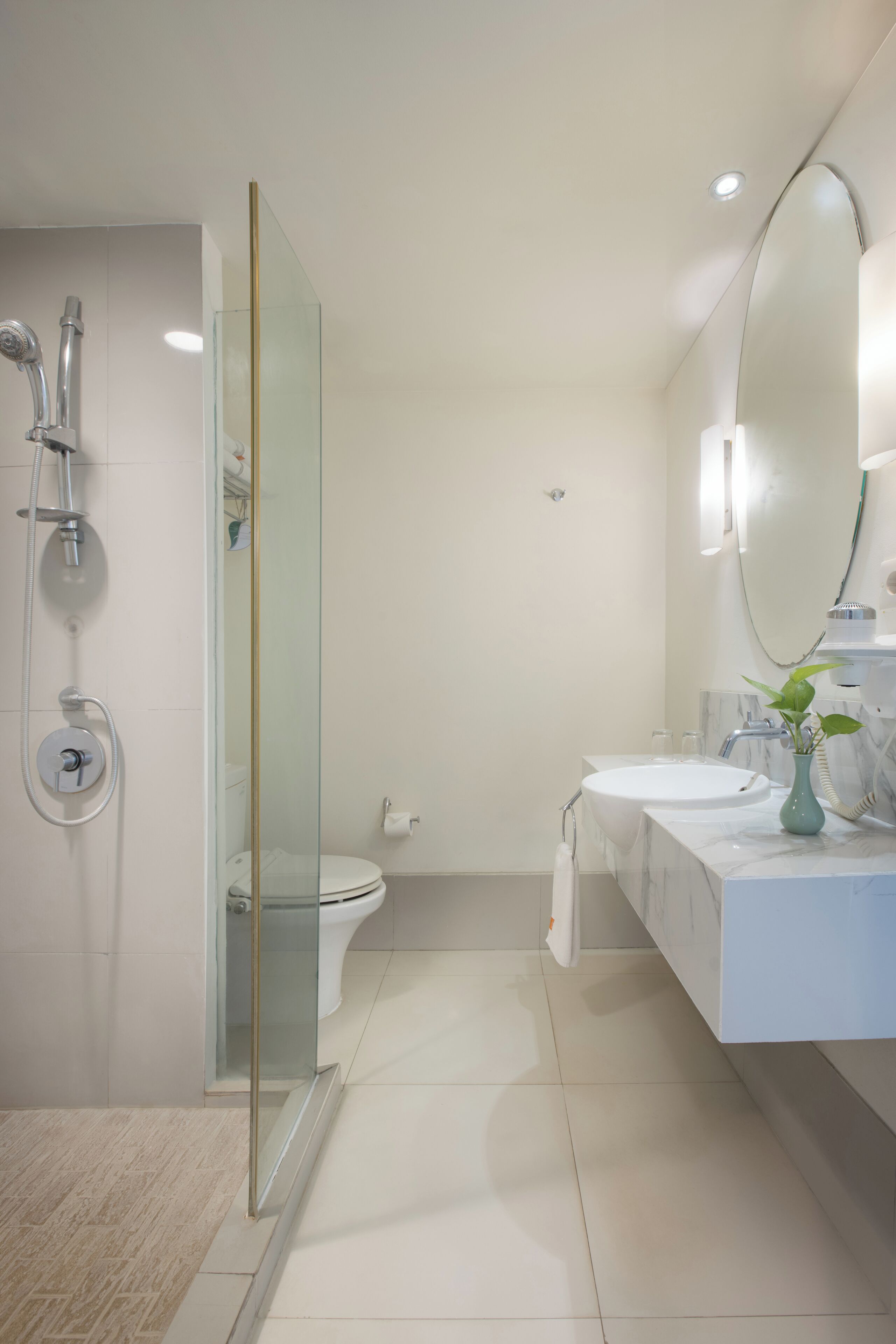 A modern bathroom with a glass-enclosed shower, a white sink, and a large mirror.