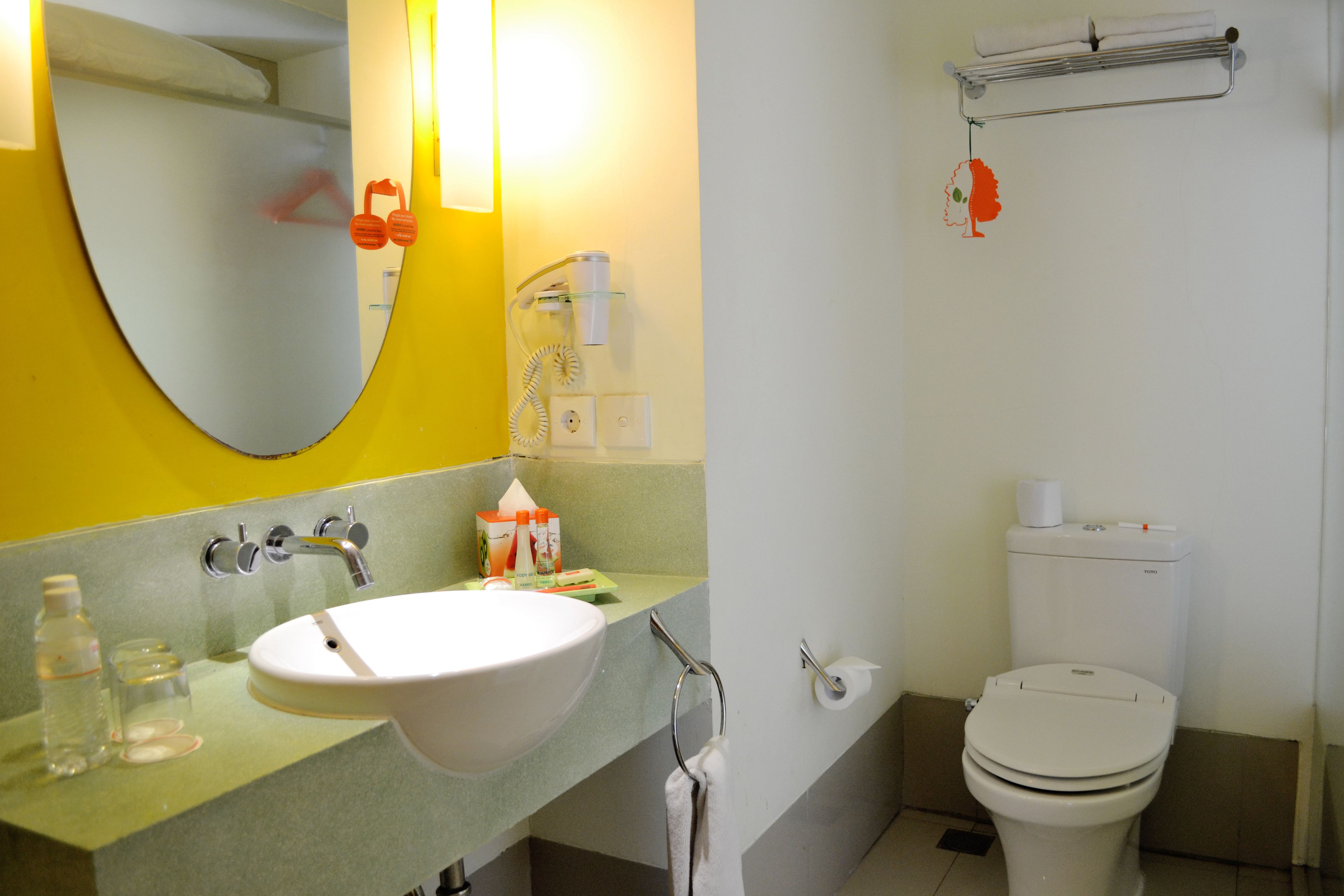 A bathroom with a sink, mirror, toilet, and towel rack.