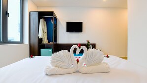 Una habitación de hotel con cama, televisor montado en la pared y armario.