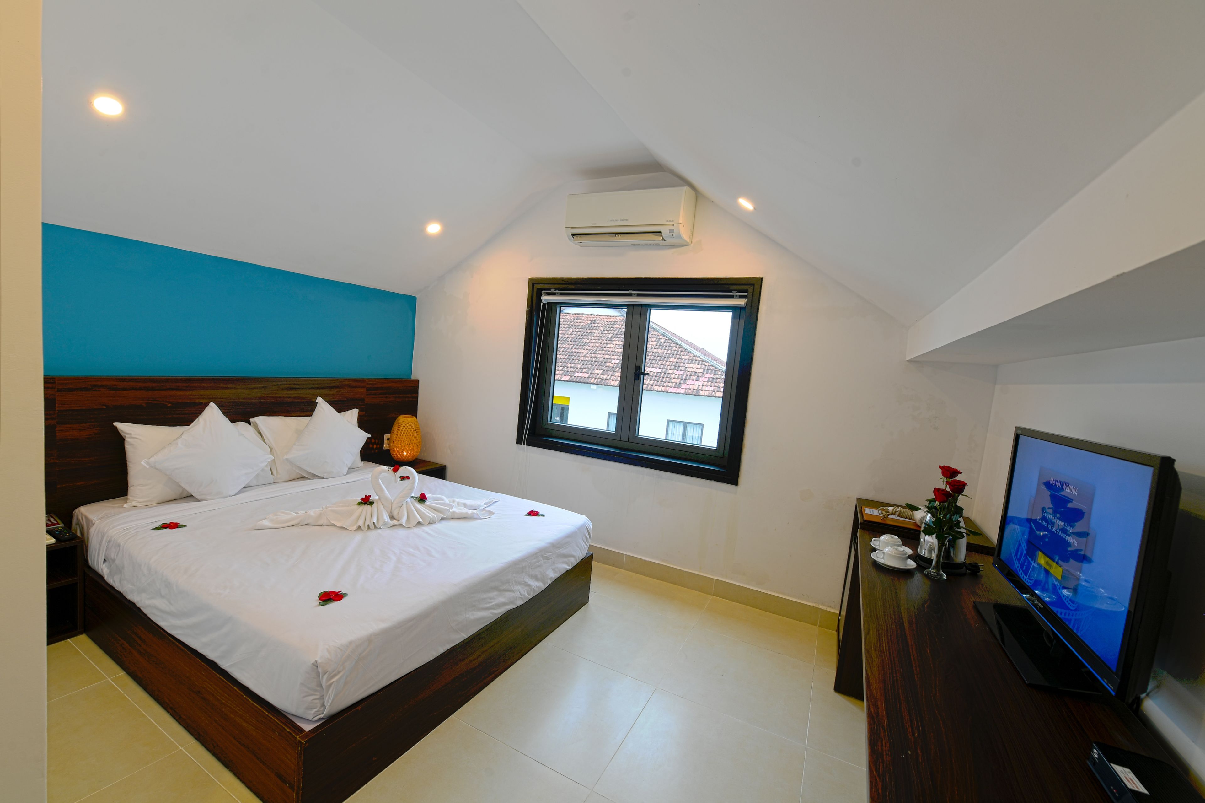 A hotel room with a bed, a television, and a window.