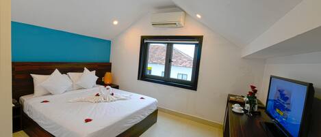 A hotel room with a bed, a television, and a window.