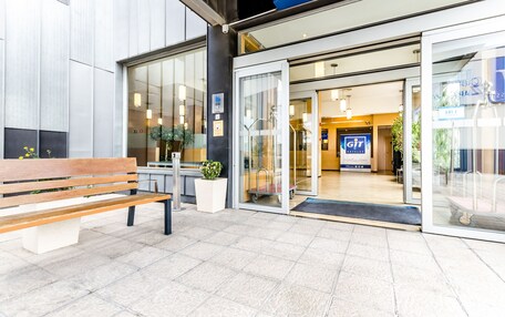 A hotel entrance with a bench, a potted plant, and a sign for GIT Hotels.
