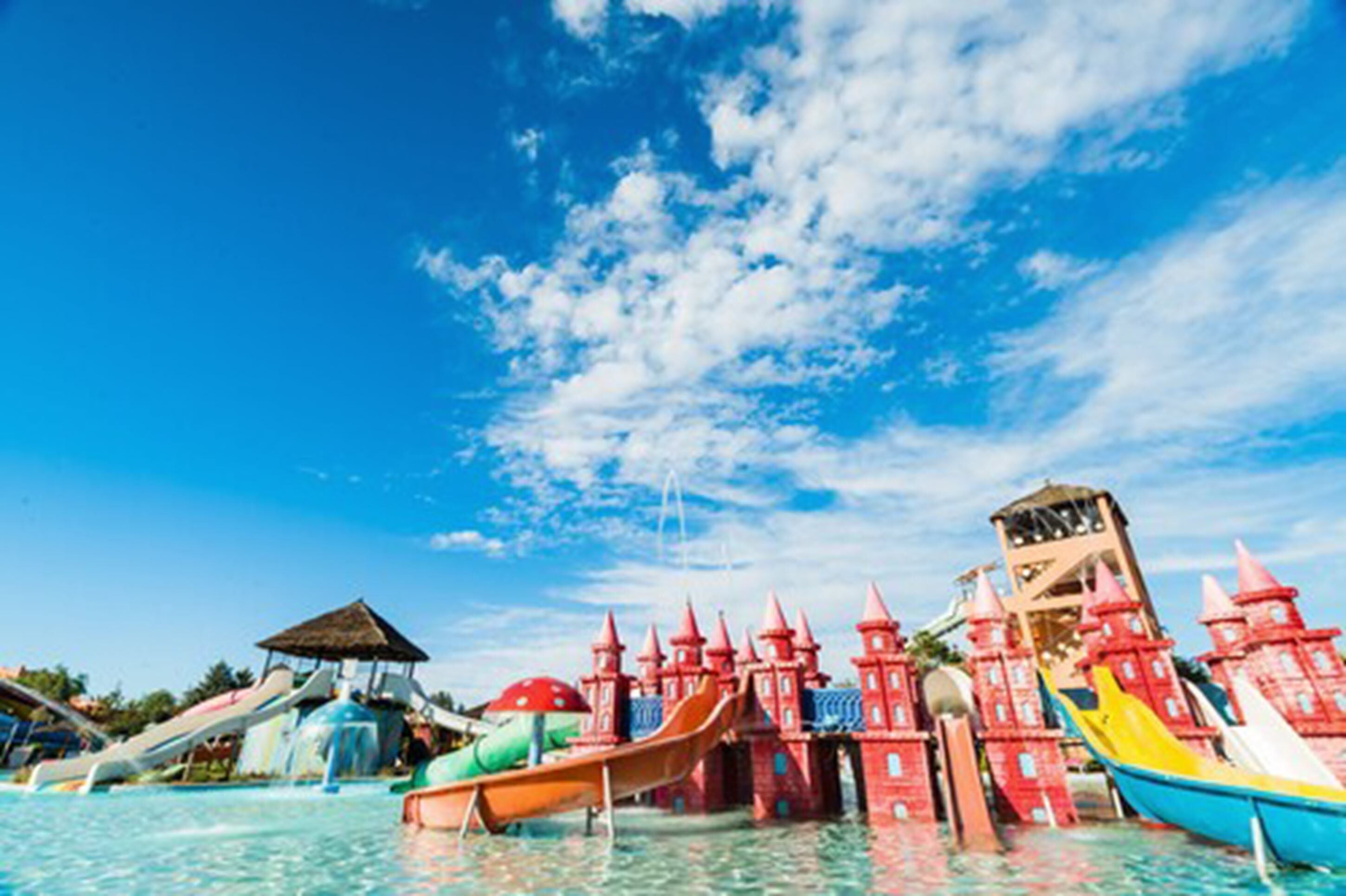Ein Wasserpark mit Rutschen und einem schlossartigen Gebäude.