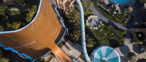An aerial view of a water park with a large brown slide, a blue spiral slide, and a pool area.