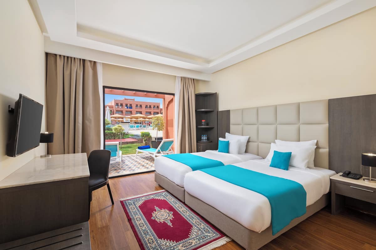 A hotel room with a bed, desk, chair, and a view of the outside.