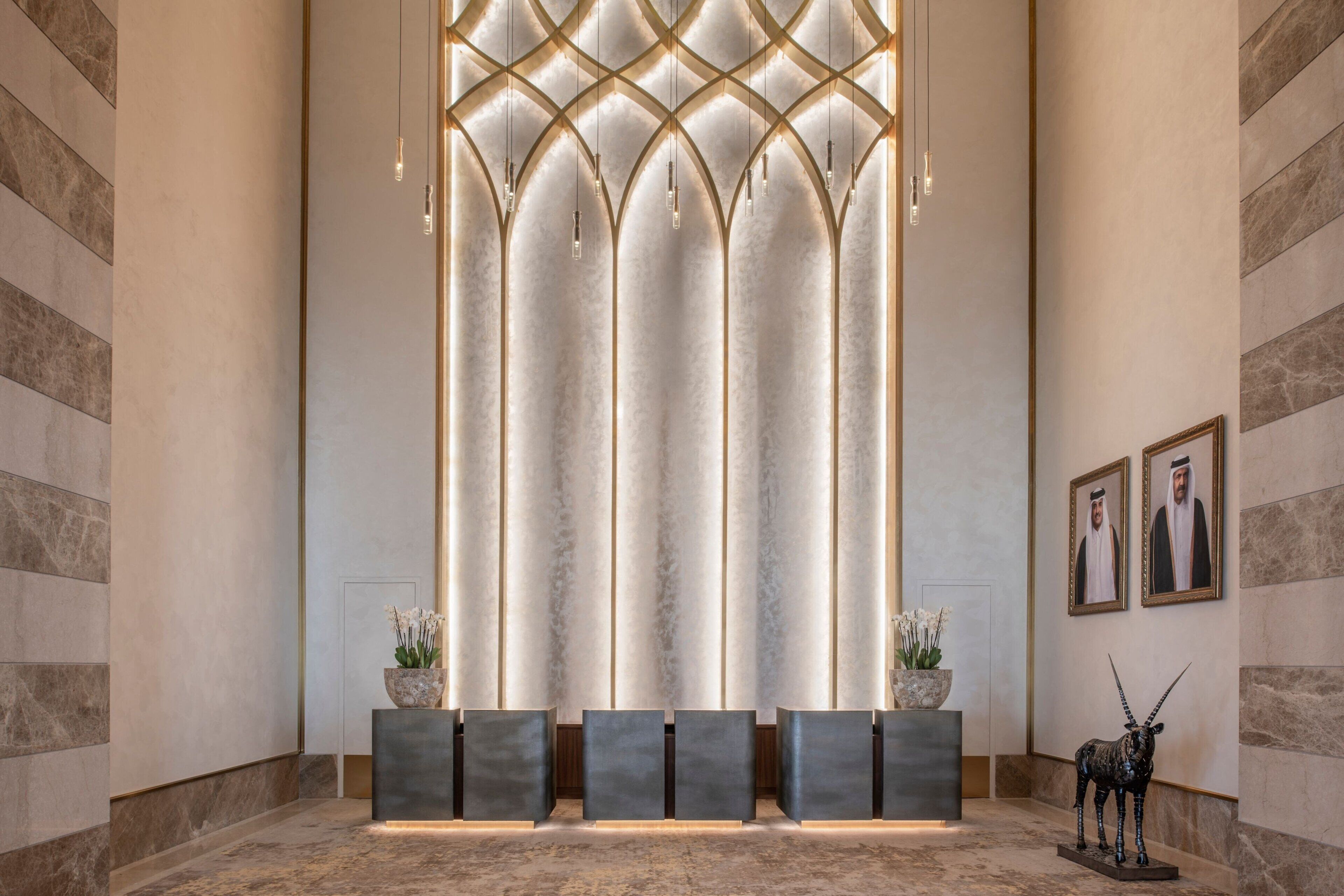 Un espace d’accueil au design moderne, comprenant un mur en marbre, un luminaire central et un comptoir d’accueil orné d’une statue d’animal décorative.