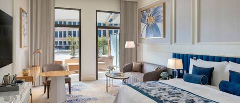 Habitación de hotel con una cama grande, un escritorio, una silla, un televisor y vistas al exterior.