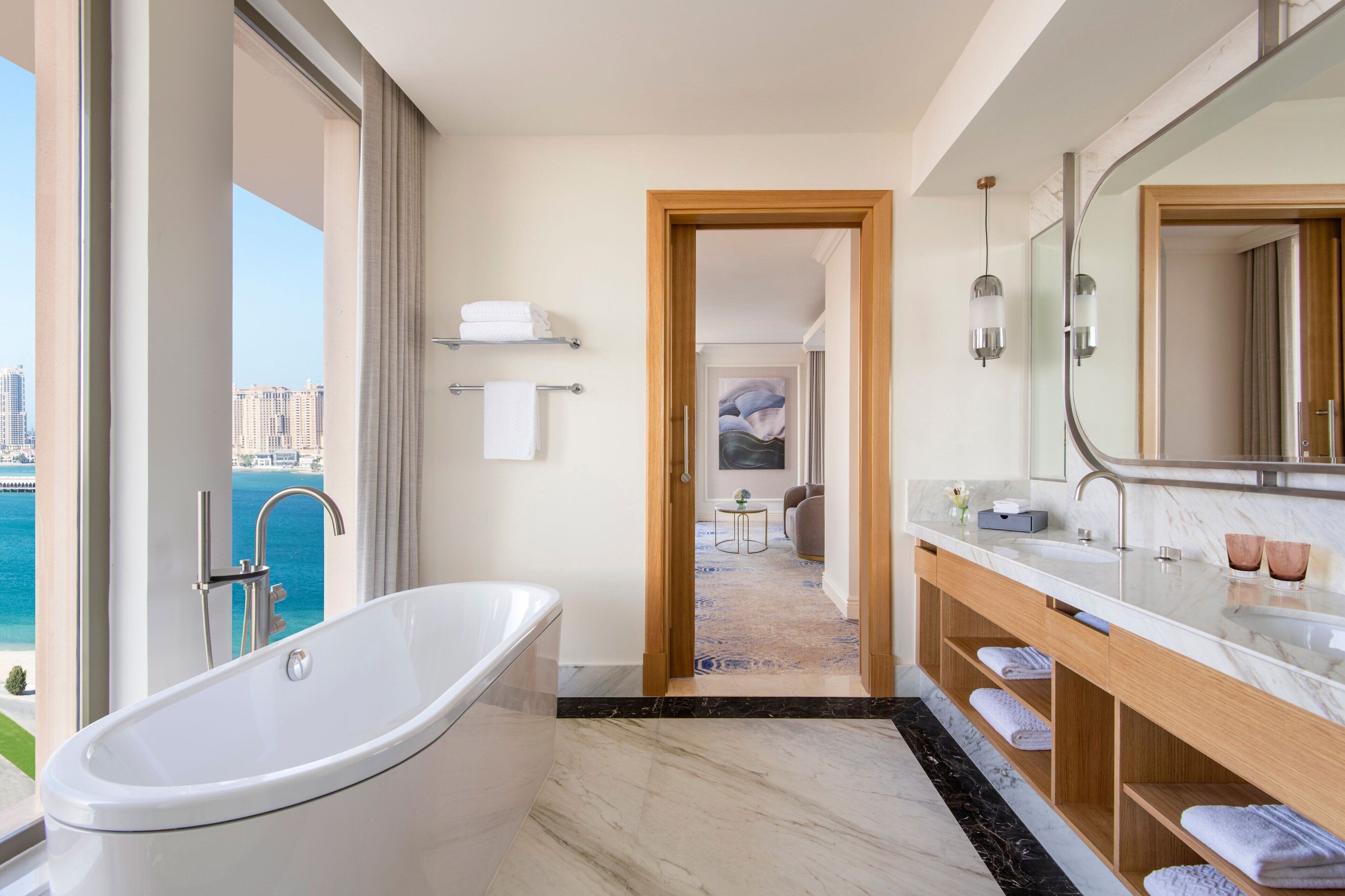 A modern bathroom with a freestanding bathtub, a large mirror, and a vanity with a marble countertop.