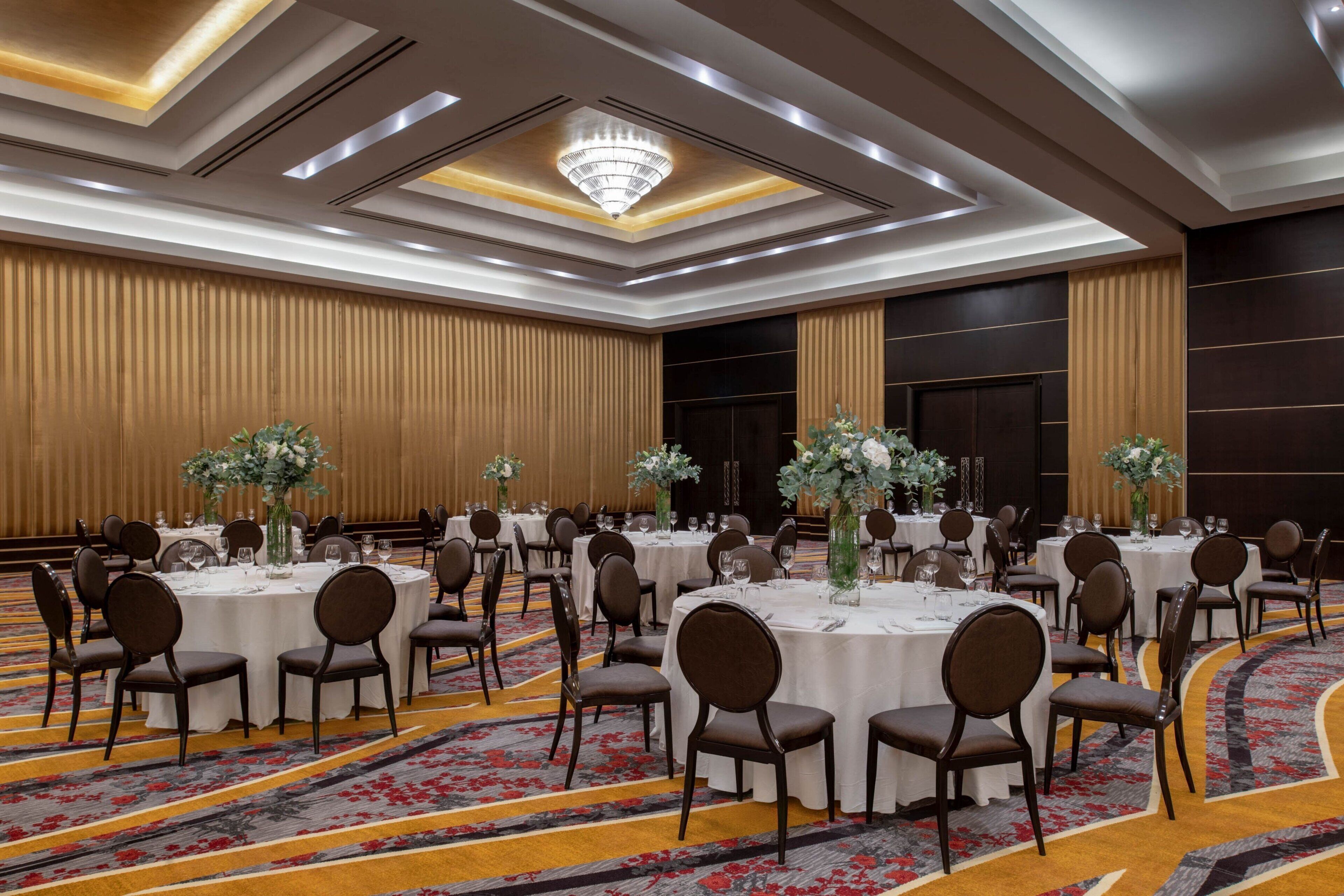 Un espai de banquet amb taules rodones, cadire i centrals florals.