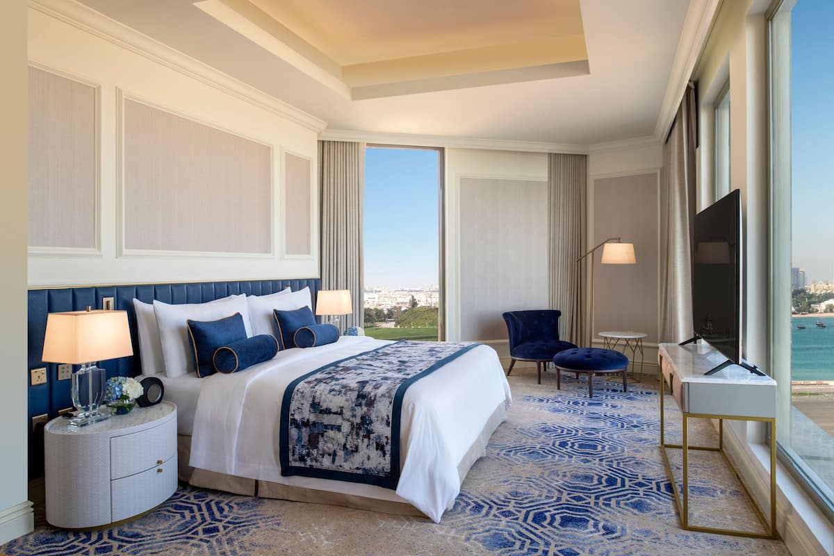 Een hotelkamer met een groot bed, een bureau, een stoel en uitzicht op zee.
