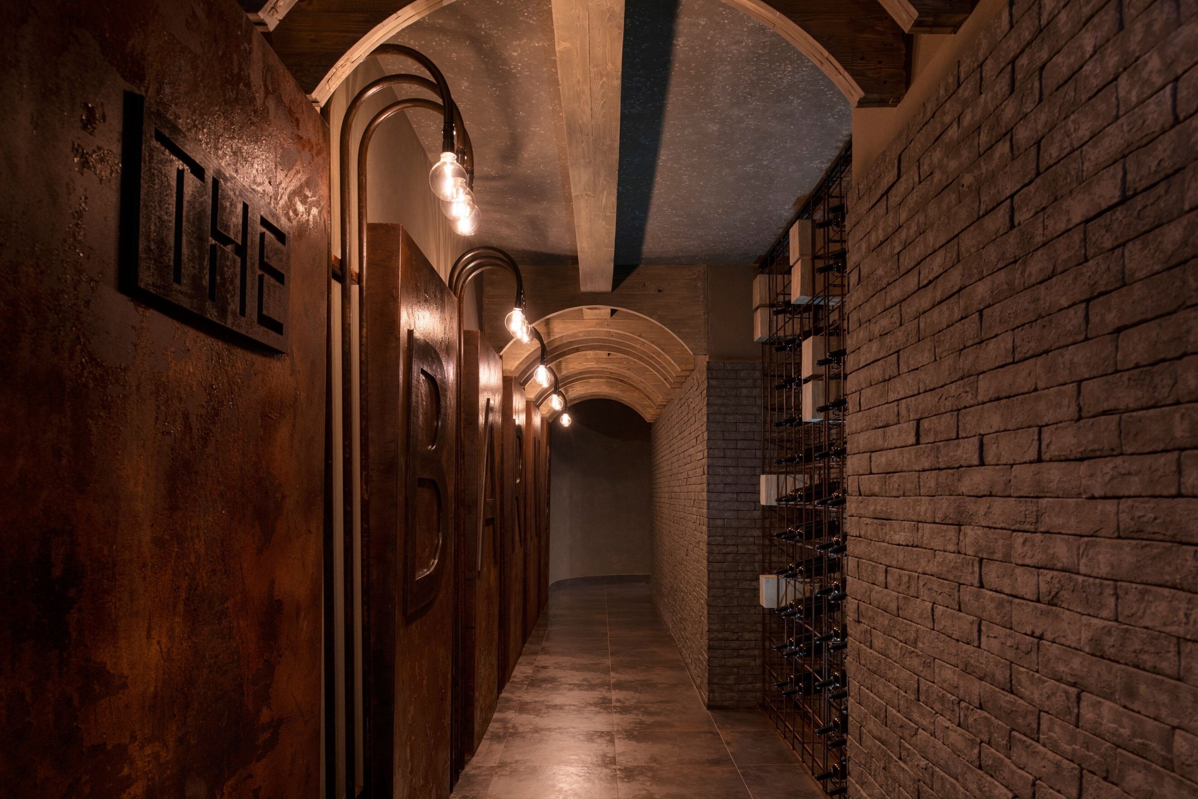 A narrow hallway with wooden doors and a brick wall on one side.