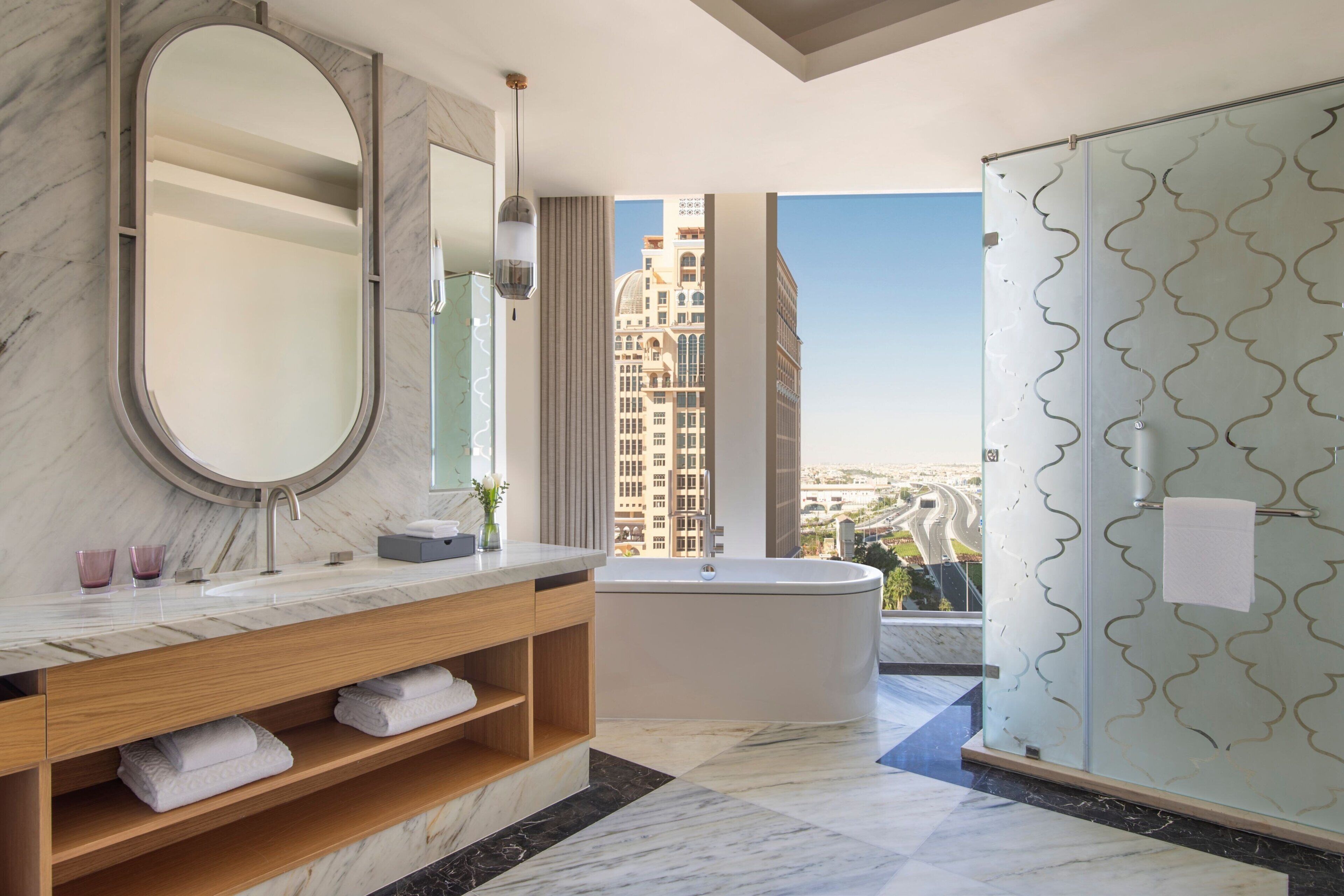 A modern bathroom with a marble vanity, a large mirror, a bathtub, and a shower with a glass door.