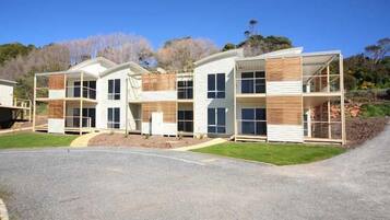 Un moderno edificio residencial de varios pisos con tejado plano, grandes ventanales y un espacio exterior cubierto.