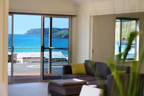 Quarto com uma grande porta de correr de vidro que dá para uma varanda com vista para o mar e falésias.