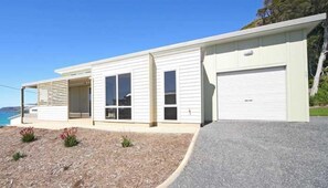 Uma casa moderna de dois andares com garagem, janelas amplas e vista para o oceano.